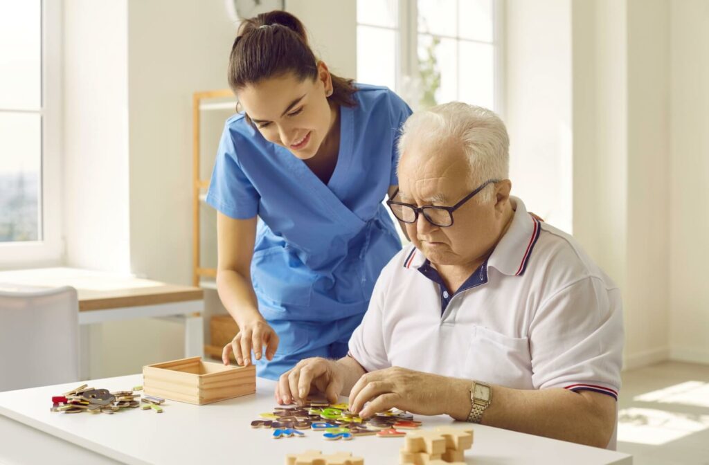 A caregiver assists a memory care resident sort through letter tiles as a cognitive exercise.