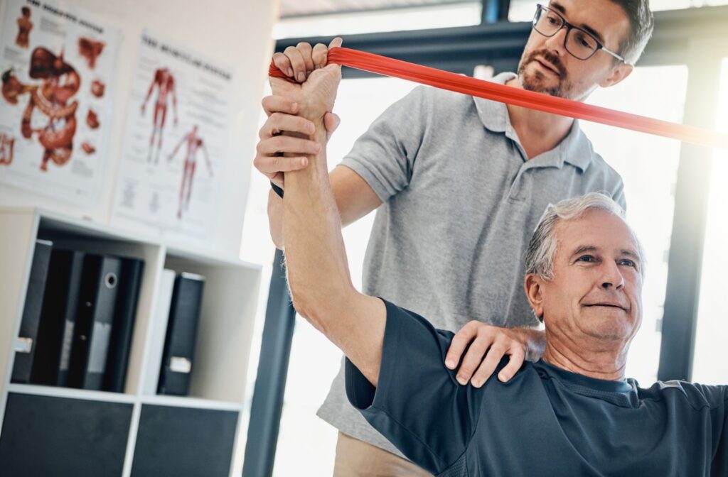 An older adult works with a physiotherapist and resistance bands to build strength and alleviate arthritis symptoms.