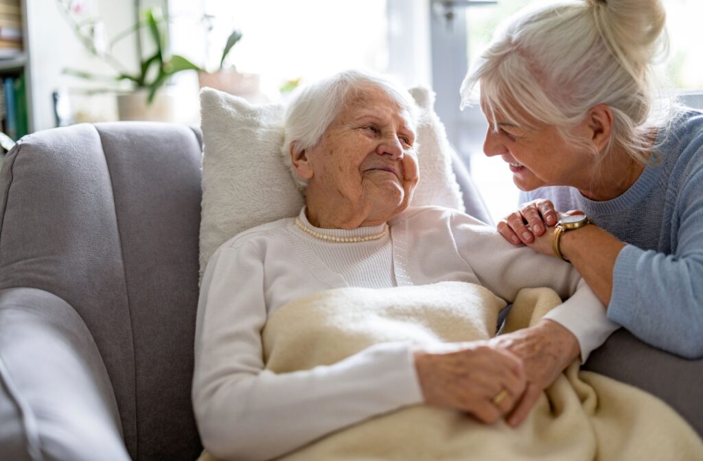 Two older adults embrace and smile at each other. One lays in a bed.