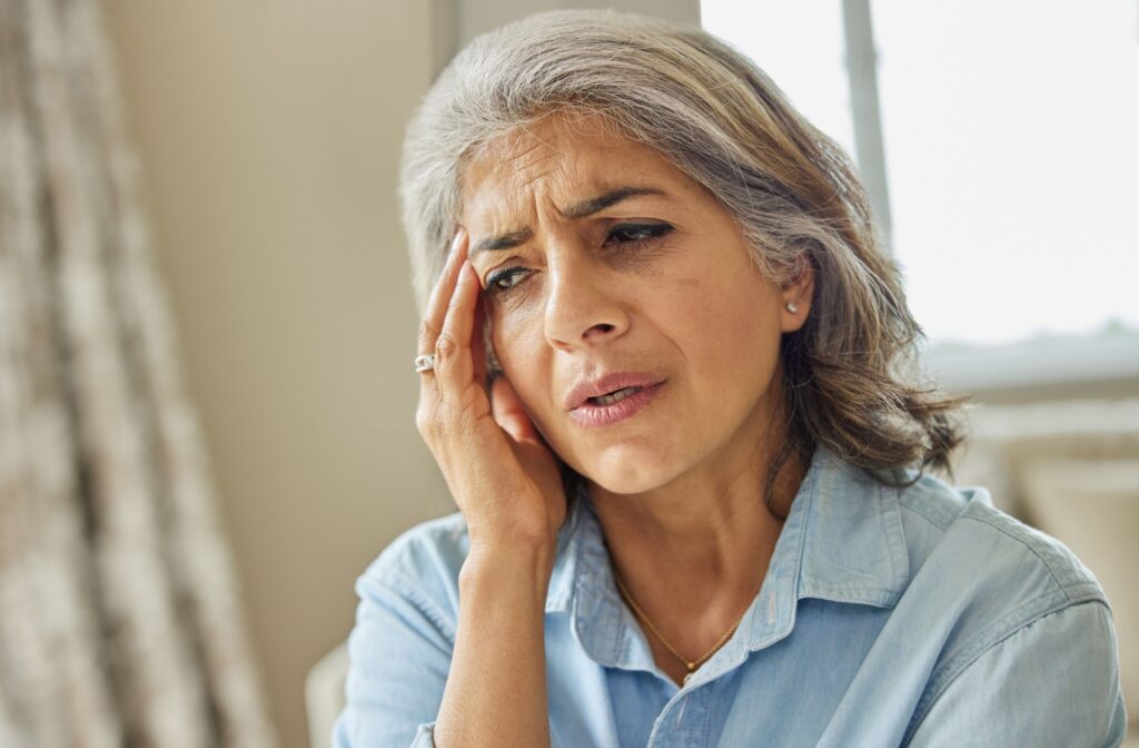 An older adult experiencing memory loss and holding their right temple.