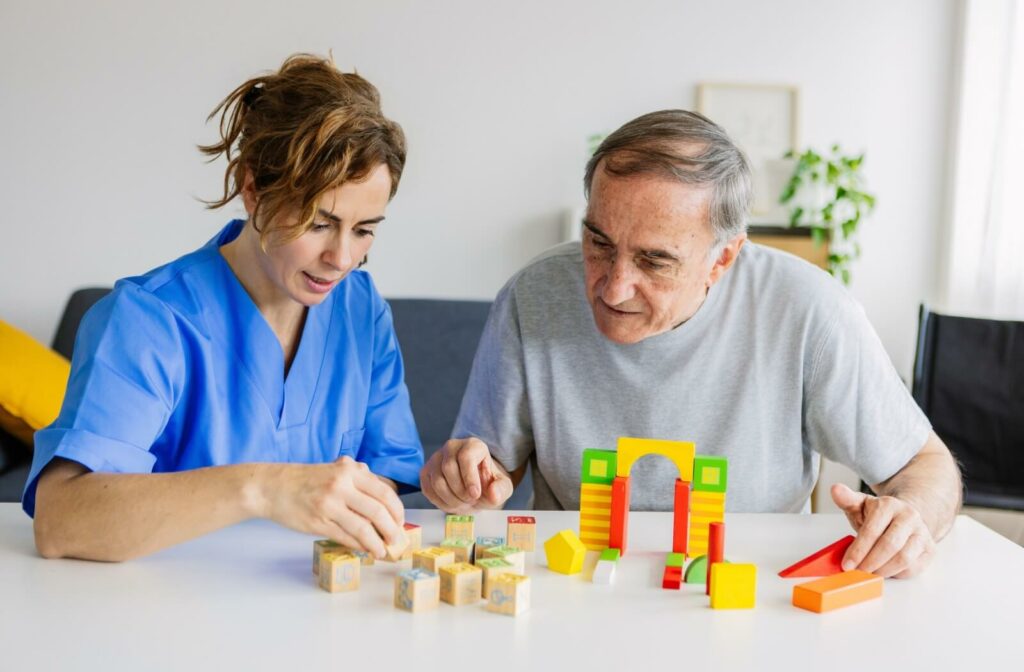 Female caregiver and senior man playing wooden shape puzzles game for dementia prevention