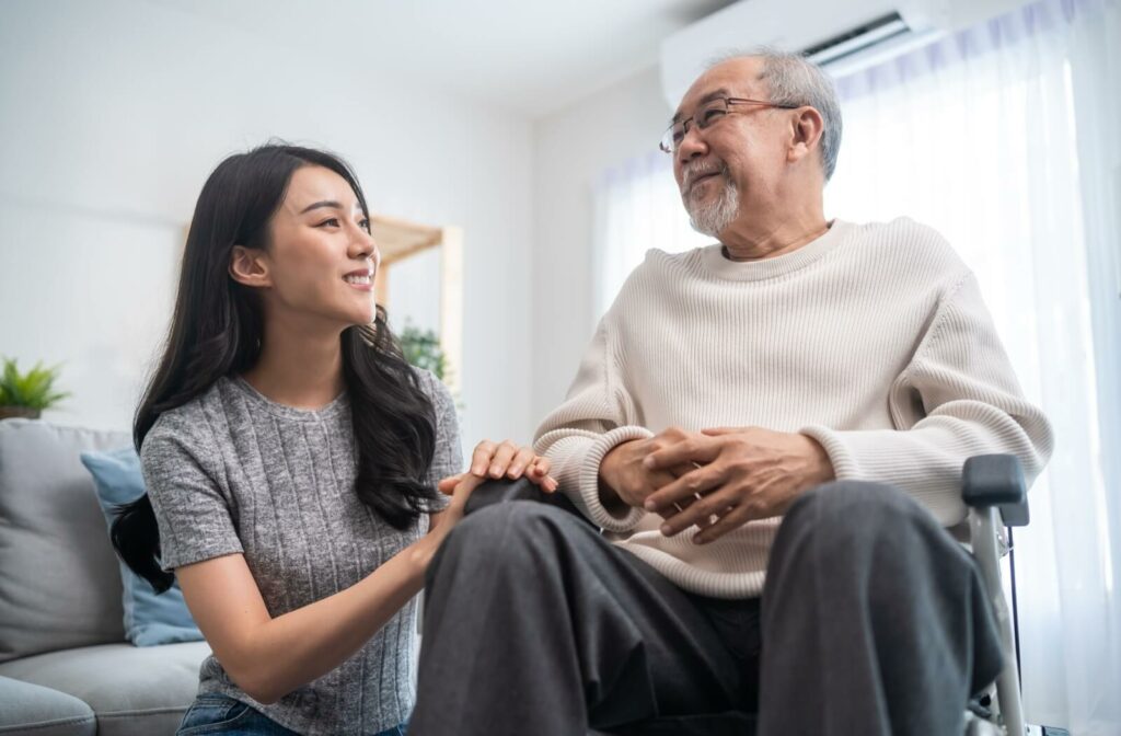daughter support older man sitting on wheelchair at home.