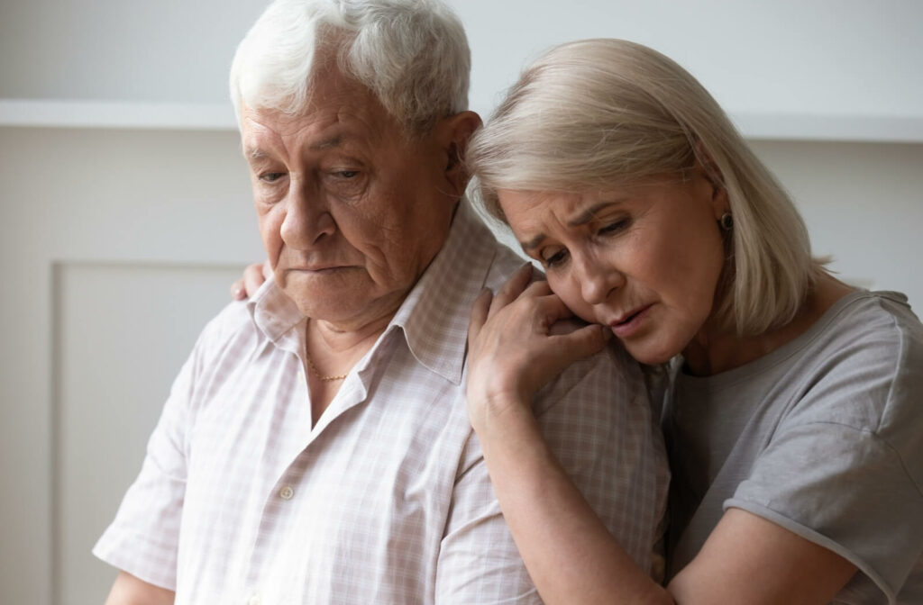 An older adult comforts their confused spouse in their home during a conversation about memory care