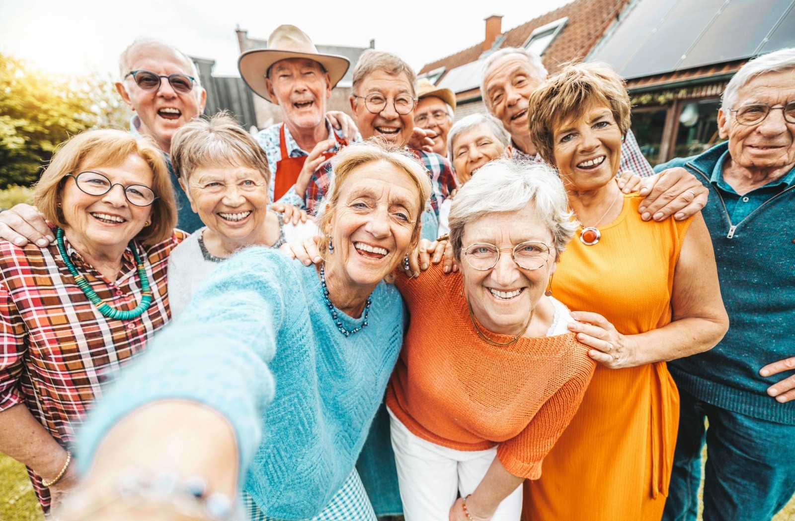 A group of senior friends in vibrantly-colored clothing smile as they take a selfie together
