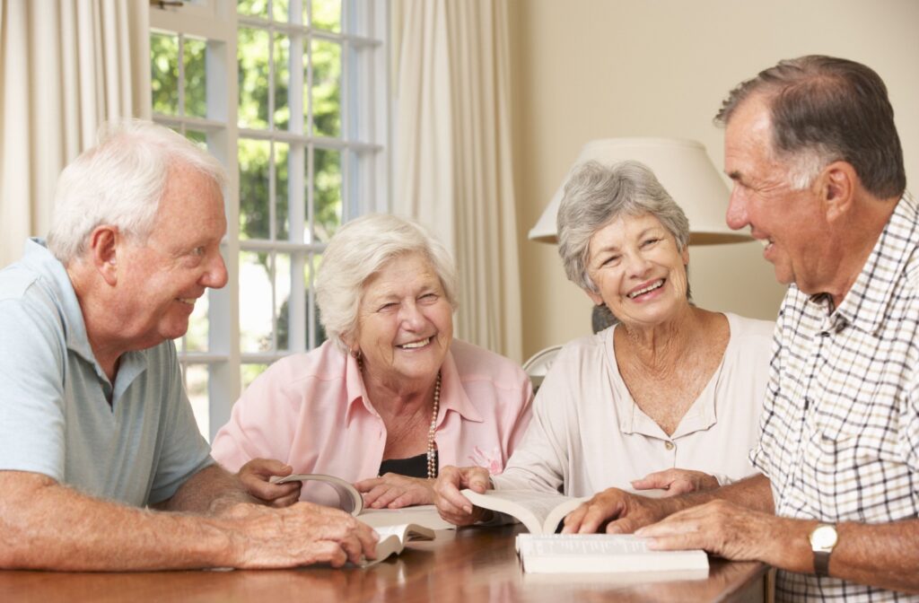 A group of senior friends in personal care enjoy reading books together.